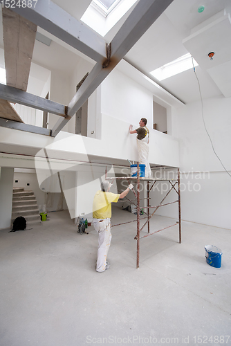 Image of construction worker using scaffold while plastering