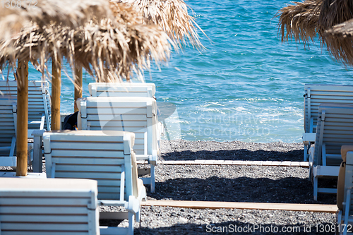 Image of beach with umbrellas and deck chairs by the sea in Santorini