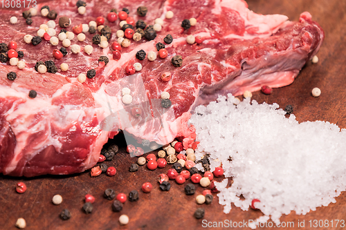 Image of steak of beef on a wooden board with spices pepper parsley salt 