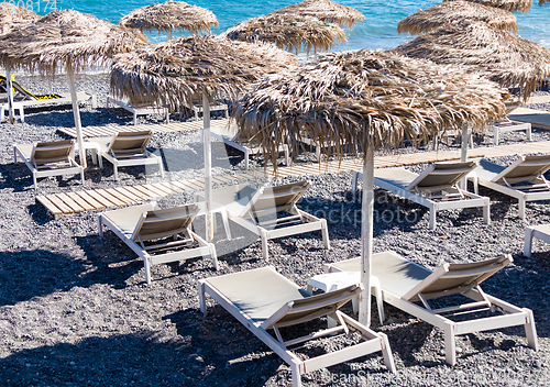 Image of beach with umbrellas and deck chairs by the sea in Santorini