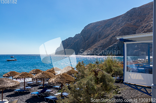 Image of beach with umbrellas and deck chairs by the sea in Santorini