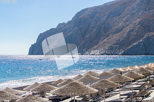 Image of beach with umbrellas and deck chairs by the sea in Santorini