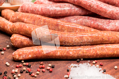 Image of raw sausages with chilli and herbs on a wooden board with spices