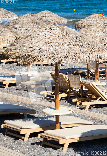 Image of beach with umbrellas and deck chairs by the sea in Santorini