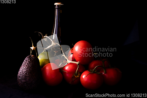 Image of large red and ripe tomatoes with lime avocado and bottle of beer