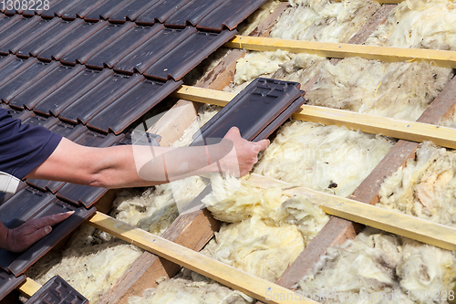 Image of a roofer laying tile on the roof