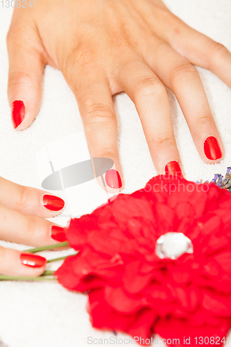 Image of Hands of a woman with red nail polish posed by an esthetician