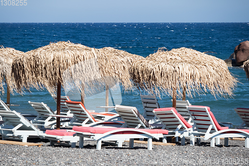 Image of beach with umbrellas and deck chairs by the sea in Santorini