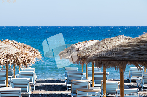 Image of beach with umbrellas and deck chairs by the sea in Santorini