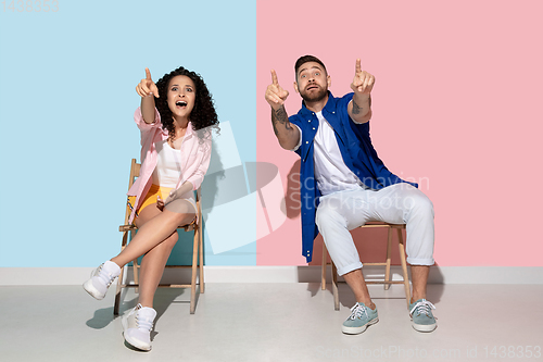 Image of Young emotional man and woman on pink and blue background