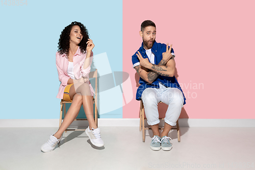 Image of Young emotional man and woman on pink and blue background