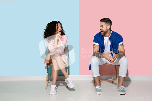 Image of Young emotional man and woman on pink and blue background