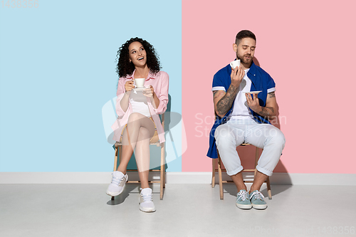 Image of Young emotional man and woman on pink and blue background