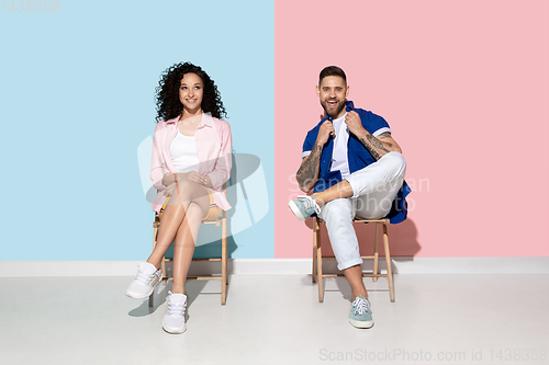 Image of Young emotional man and woman on pink and blue background