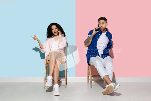 Image of Young emotional man and woman on pink and blue background