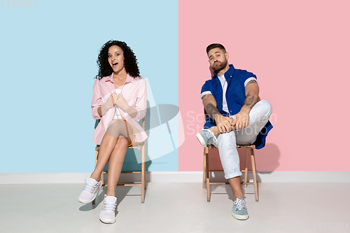 Image of Young emotional man and woman on pink and blue background