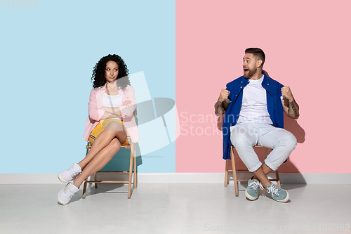 Image of Young emotional man and woman on pink and blue background