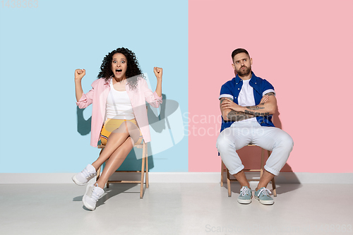 Image of Young emotional man and woman on pink and blue background