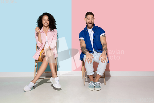 Image of Young emotional man and woman on pink and blue background
