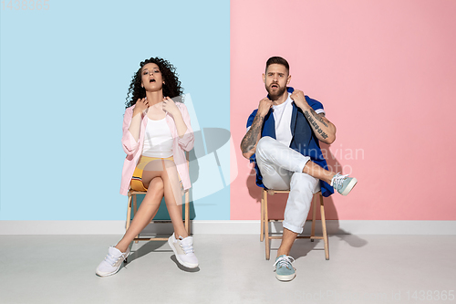 Image of Young emotional man and woman on pink and blue background