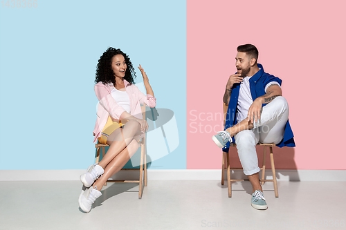 Image of Young emotional man and woman on pink and blue background