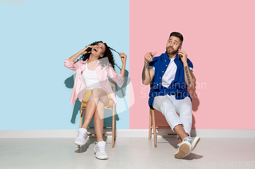 Image of Young emotional man and woman on pink and blue background