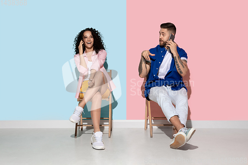 Image of Young emotional man and woman on pink and blue background