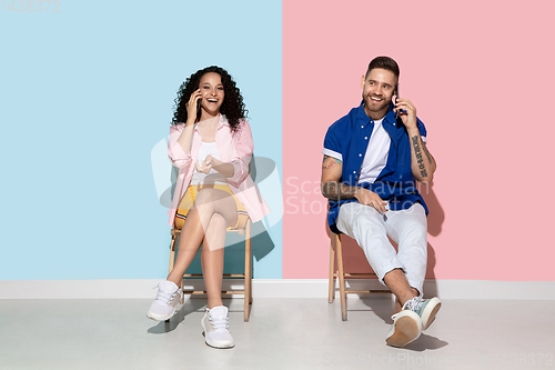 Image of Young emotional man and woman on pink and blue background