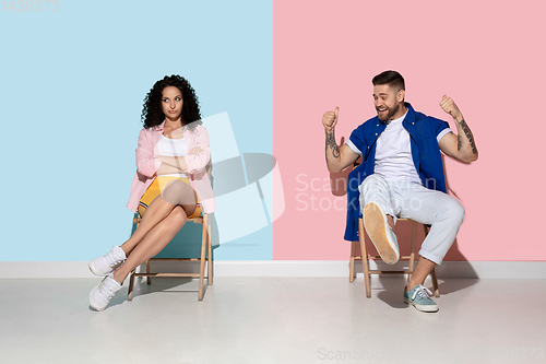 Image of Young emotional man and woman on pink and blue background