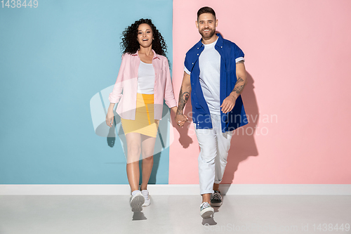 Image of Young emotional man and woman on pink and blue background