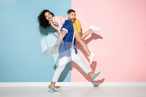 Image of Young emotional man and woman on pink and blue background