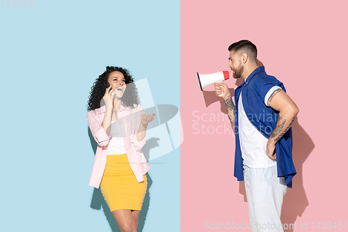 Image of Young emotional man and woman on pink and blue background