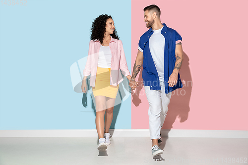 Image of Young emotional man and woman on pink and blue background