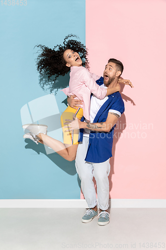 Image of Young emotional man and woman on pink and blue background