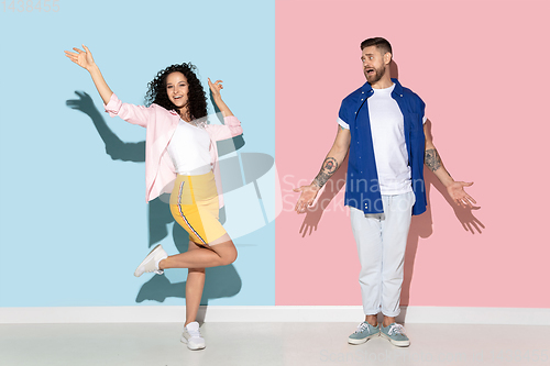 Image of Young emotional man and woman on pink and blue background