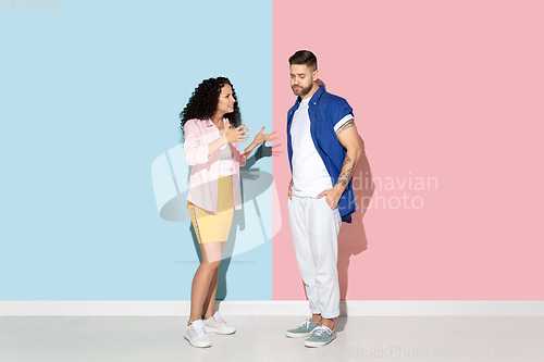 Image of Young emotional man and woman on pink and blue background