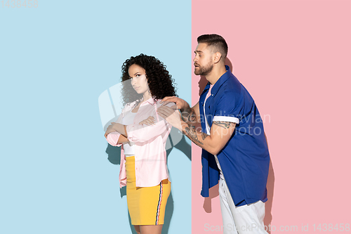 Image of Young emotional man and woman on pink and blue background