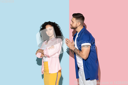 Image of Young emotional man and woman on pink and blue background