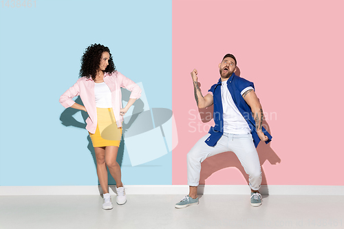 Image of Young emotional man and woman on pink and blue background