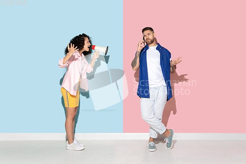 Image of Young emotional man and woman on pink and blue background