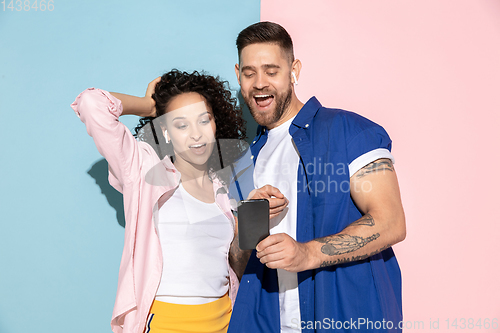 Image of Young emotional man and woman on pink and blue background