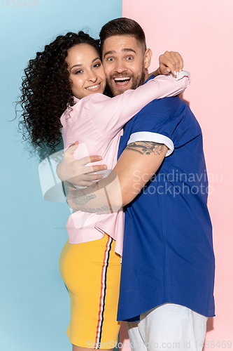 Image of Young emotional man and woman on pink and blue background