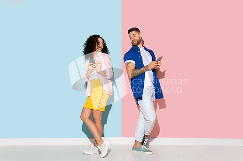 Image of Young emotional man and woman on pink and blue background