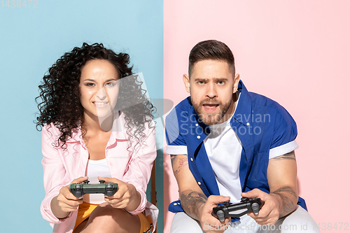 Image of Young emotional man and woman on pink and blue background