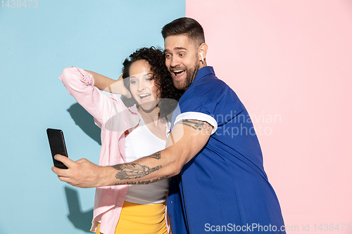 Image of Young emotional man and woman on pink and blue background