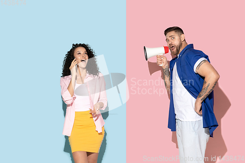 Image of Young emotional man and woman on pink and blue background