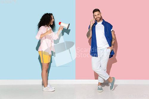 Image of Young emotional man and woman on pink and blue background