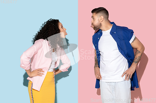 Image of Young emotional man and woman on pink and blue background