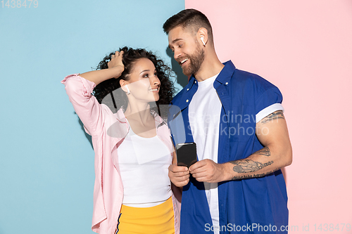 Image of Young emotional man and woman on pink and blue background