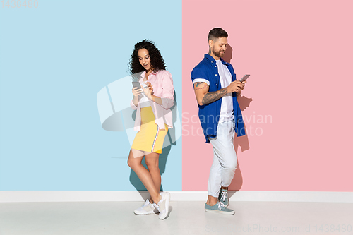 Image of Young emotional man and woman on pink and blue background